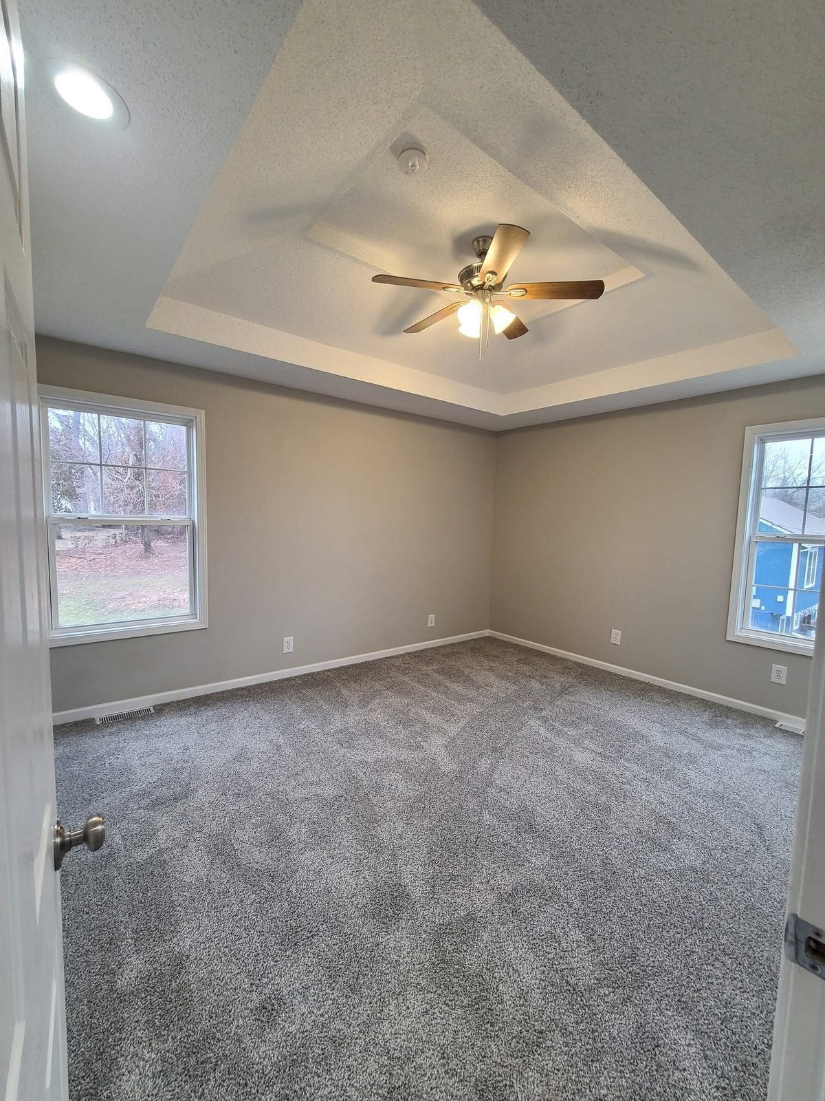 Primary bedroom with tray ceiling and new carpet